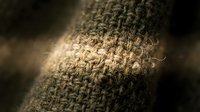 Close-up macro shot of natural burlap fabric texture showing detailed weave pattern and fiber structure in warm brown tones with soft lighting.