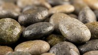 Smooth river stones in natural earth tones create calming zen atmosphere for spa treatments, meditation spaces, and wellness design projects.