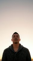 Male individual of East Asian descent wearing a charcoal knit cardigan against a serene twilight sky. Suitable for lifestyle, wellness, portrait, and contemplative themes.