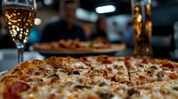 Delicious pizza slices with melted cheese and toppings served in restaurant setting with sparkling drinks creating warm dining atmosphere for food lovers.