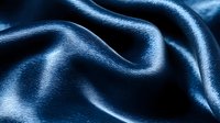 Luxurious navy blue silk fabric with elegant waves and folds creating smooth curves and highlights. Soft textile background with rich satin sheen and flowing movement.