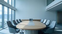 Modern corporate boardroom with oval wooden conference table and gray chairs overlooking city skyline through floor-to-ceiling windows for business meetings.