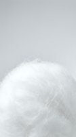 Cotton candy cloud of white spun sugar against neutral background. Fluffy confectionery texture ideal for dessert, candy shop, bakery, and sweet treat marketing materials.