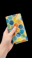 Hand holding colorful honeycomb patterned beeswax wrap, isolated on transparent background. Ready for eco, kitchen, and sustainable living design projects.