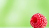 Fresh red raspberry on soft green blurred background for healthy eating, organic food concepts, summer fruit photography and natural nutrition designs.