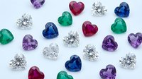 Colorful heart-shaped gemstones and brilliant cut diamonds scattered on white background. Luxury jewelry collection with emerald, sapphire, ruby, amethyst stones.