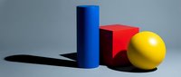 Geometric shapes including blue cylinder, red cube, and yellow sphere arranged on neutral background with dramatic shadows for design and composition concepts.