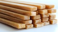Stack of natural honey sticks on white background, close up view of sweet candy cane shaped treats made from pure honey, ready for packaging and retail.