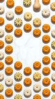Colorful mini pumpkins and gourds arranged in repeating pattern on white marble background for autumn harvest seasonal decoration and fall holiday designs.