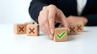 Business professional selecting green checkmark wooden block among red X blocks representing quality choice and decision making process.