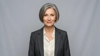 Mature woman with gray hair wearing dark blazer and white blouse, professional headshot for corporate, business, and executive roles.