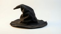 Worn black wizard hat with curved pointed tip and weathered fabric texture on white background isolated for Halloween costume design.