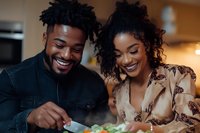 Young African American couple enjoying healthy meal together at home kitchen table smiling and bonding over nutritious food in warm domestic setting.