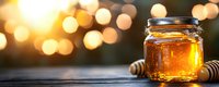 Glass jar of fresh golden honey with wooden dipper on rustic table against blurred warm bokeh lights background, natural sweetener panoramic shot.