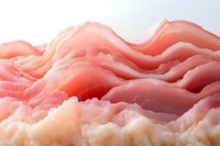 Thin slices of pink prosciutto ham arranged in wavy layers creating abstract landscape pattern, showcasing delicate texture and marbling for food photography.