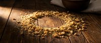 Scattered popcorn kernels and popped corn arranged in circle on rustic wooden surface with bowl, suitable for food photography and snack marketing.