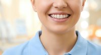 Young Asian female healthcare worker with dental braces smiling confidently in medical uniform at clinic showing orthodontic treatment and professional care.
