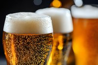 Fresh cold lager beer with bubbles and foam in glass, macro shot with selective focus and bokeh lights in dark background for bar menu design.