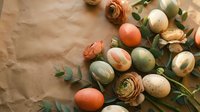 Easter eggs in natural earth tones with ranunculus flowers and eucalyptus branches on kraft paper background for spring holiday decorating.