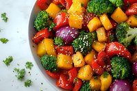 Fresh colorful vegetable salad with butternut squash, broccoli, red onion, bell peppers and sesame seeds on white background, healthy food styling.
