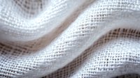 Clean white linen fabric with natural texture and soft waves creates gentle folds and shadows, macro close up view showing detailed weave pattern and textile structure.