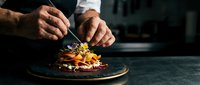 Professional chef hands garnishing gourmet dish with microgreens in upscale restaurant kitchen. Culinary artistry and fine dining presentation concept.