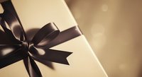 Luxury gift box with black ribbon bow on neutral background with soft bokeh lighting, suitable for holiday, celebration, and promotional design projects.