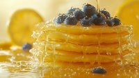 Golden honeycomb dripping with fresh honey topped with blueberries on wooden surface. Natural organic sweetness for healthy breakfast and cooking.