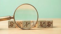 Business skills development concept with wooden blocks and magnifying glass for professional growth and career advancement training.