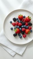Fresh mixed berries on white ceramic plate with linen napkin for healthy eating and nutrition concepts.