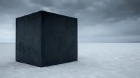 Dark cube structure standing alone on frozen winter landscape with overcast sky and minimalist composition.