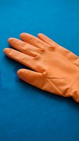 Orange rubber cleaning glove on blue background, isolated for design use on promotional materials, websites, and household product packaging.