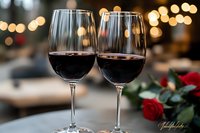 Two glasses of red wine with romantic bokeh lights in background and red rose, elegant restaurant setting for anniversary or Valentine's Day celebration.