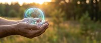 Hands holding glowing Earth globe with warm sunset light, symbolizing environmental protection, sustainability and global responsibility for planet care.
