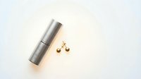 Modern silver lipstick tube with golden scales of justice on white background for cosmetics and legal concept designs.