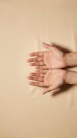 Open hands reaching out in welcoming gesture on neutral beige background for wellness and care concepts.