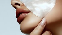 Close up of sensual plump lips with matte brown lipstick and manicured finger touching chin against light background, beauty and cosmetics concept.