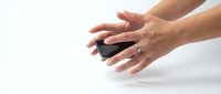 Two hands with medium skin tone holding a black smartphone on white background, isolated for app design and technology marketing use.