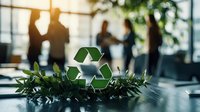 Green recycling symbol with natural leaves on office desk, business people silhouettes in background discussing sustainability and environmental solutions.