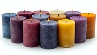 Colorful pillar candles arranged in rows showing variety of autumn and winter colors including blue, burgundy, purple, and golden yellow on white background.