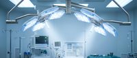 Modern operating room with bright surgical lights and medical equipment ready for healthcare procedures in sterile hospital environment.