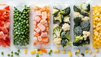 Frozen vegetables and fruits in plastic containers arranged in rows showing variety of colorful produce including red peppers, peas, carrots, broccoli and corn.