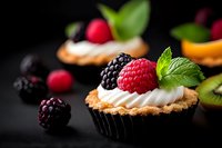 Gourmet cupcakes topped with fresh berries and mint on dark background. Elegant dessert presentation for bakery menus, food blogs and culinary marketing.