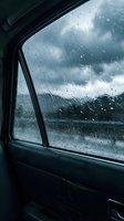 Raindrops on car window during storm with dramatic cloudy sky and mountain landscape view from inside vehicle interior for travel and weather concepts.