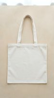 Blank white cotton tote bag with long handles displayed flat on neutral beige background. Isolated design ready for mockups, branding, and merchandise customization projects.
