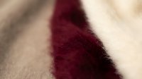 Close-up of burgundy red knitted wool fabric texture with soft focus and warm lighting creating cozy winter fashion background for textile design.