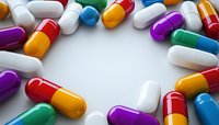 Colorful pharmaceutical capsules and pills arranged in circular frame on white background. Medical and healthcare concept with copy space for text.