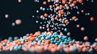 Colorful sprinkles or sugar pearls falling onto a pile, creating dynamic motion against dark background. Macro photography captures vibrant coral, blue and white decorative elements.