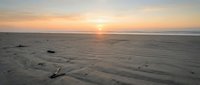 Serene coastal landscape at golden hour with calm ocean waters and sandy beach during sunset or sunrise, suitable for travel and nature backgrounds.