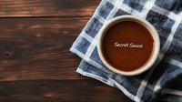 Brown sauce in white ceramic bowl on checkered blue napkin against rustic wooden table background, overhead view for food photography and menu design.